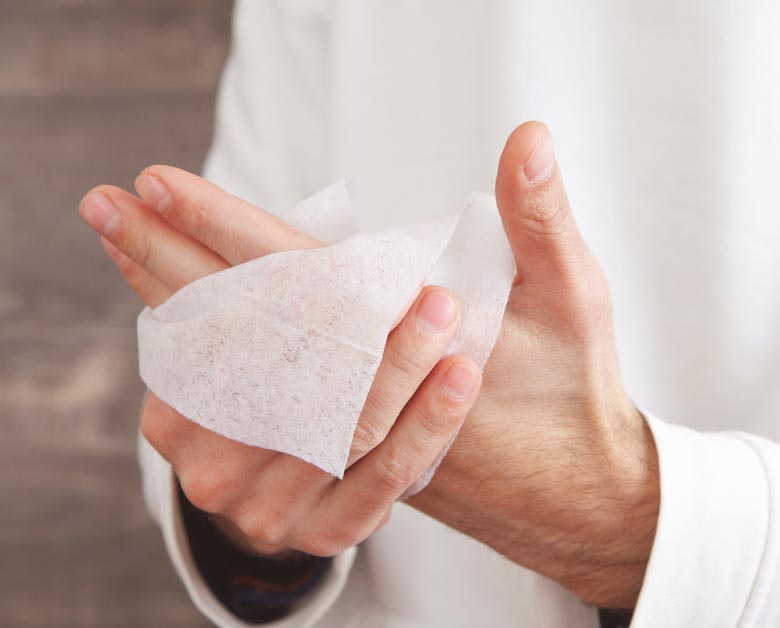 Ein Mann reinigt eine Hände mit einem Pflegetuch.